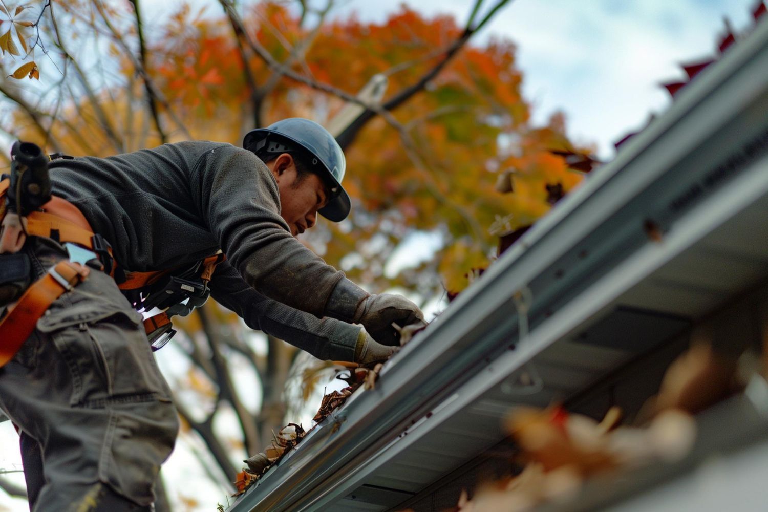 A man is working on a gutter on the roof of a house.