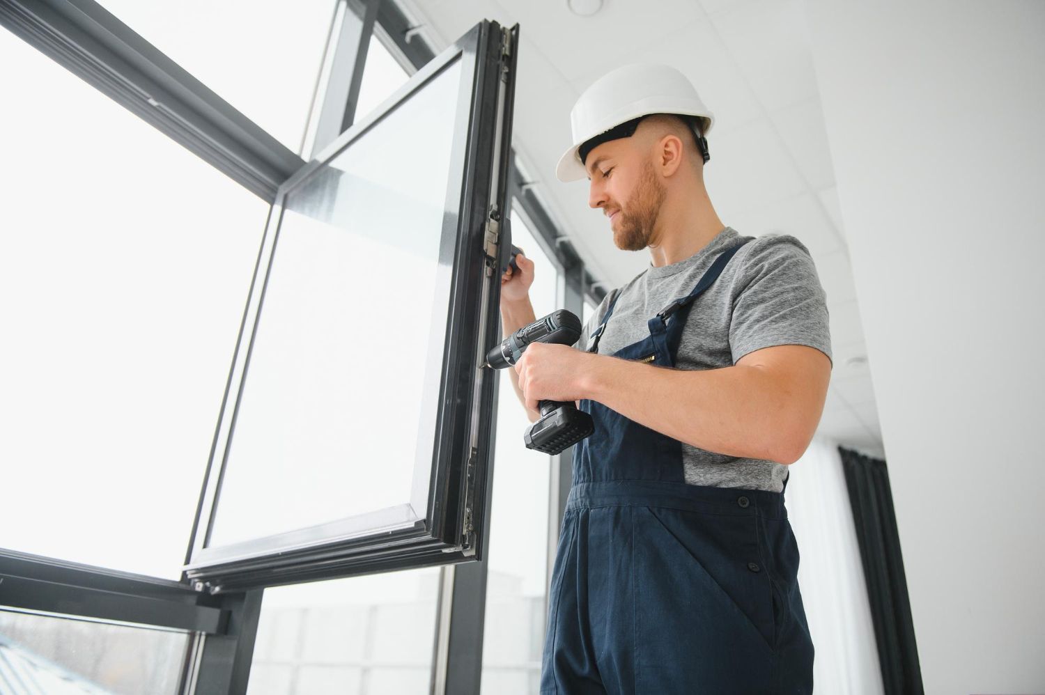 A man is installing a window with a drill.