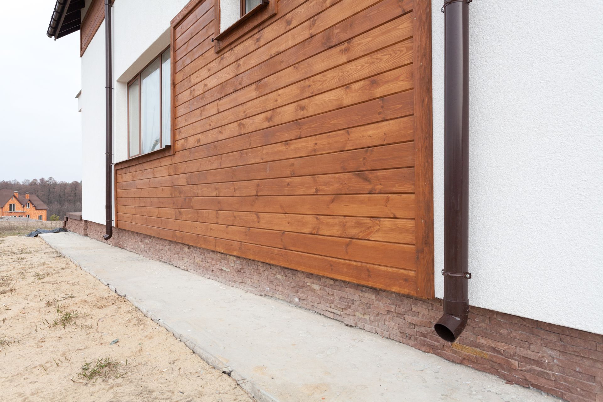 The side of a house with wooden siding and a drainpipe.