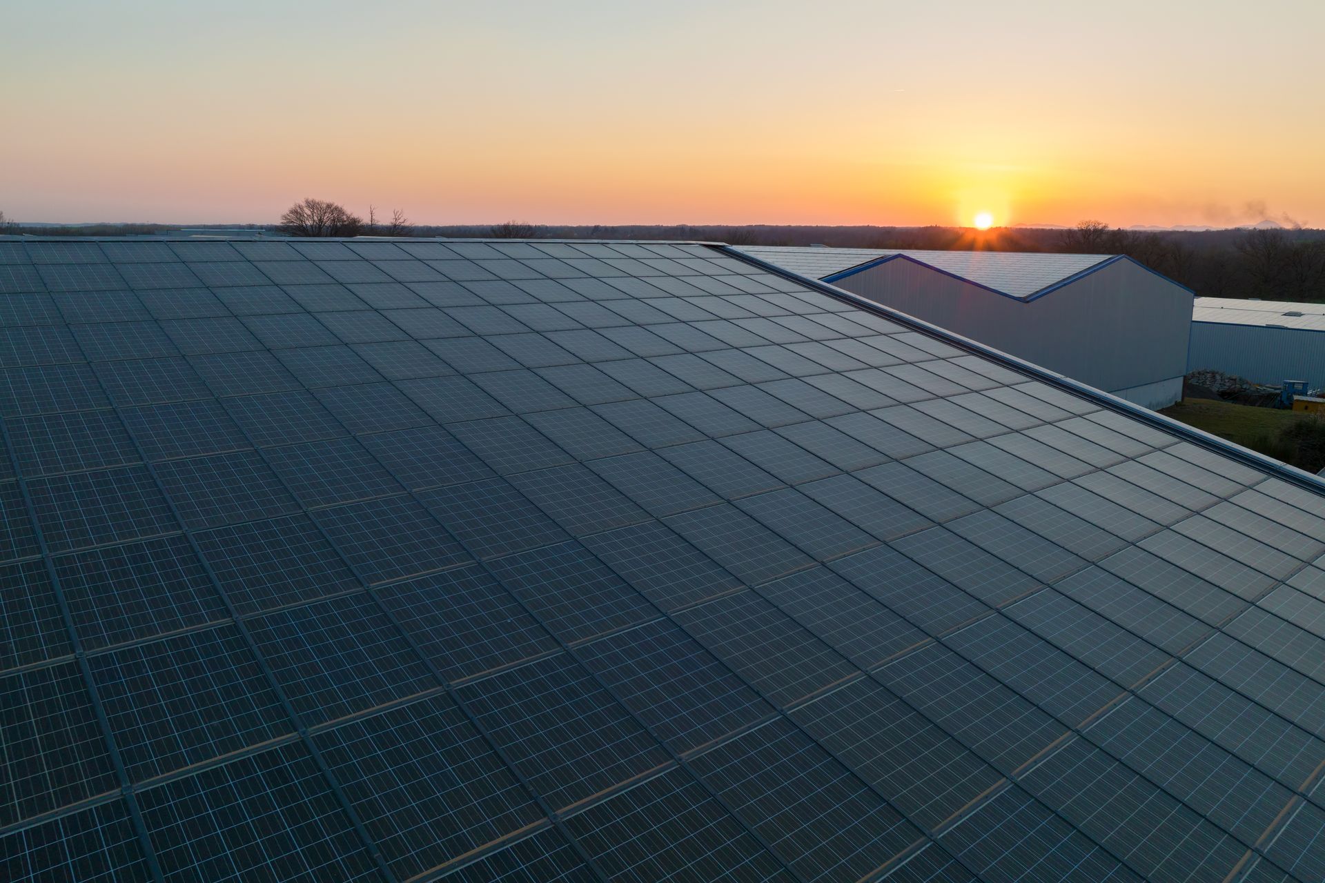 The sun is setting behind the solar panels on the roof
