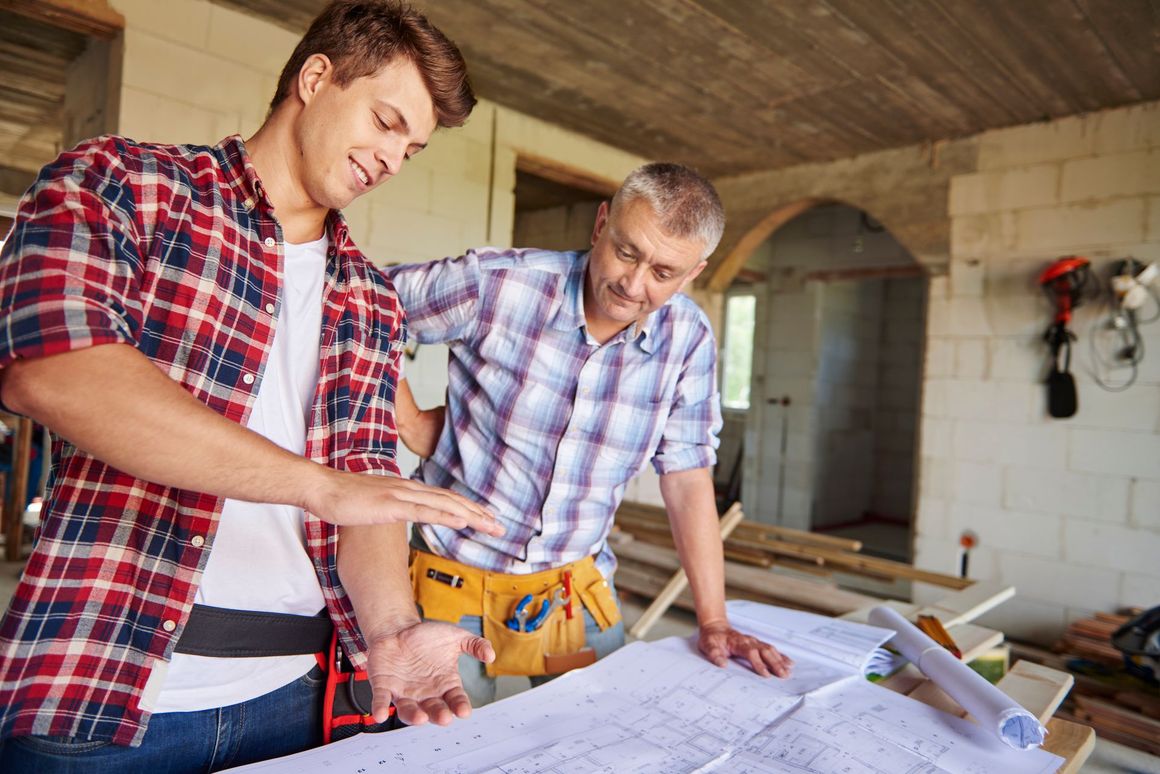 Two men are looking at a blueprint in a construction site.