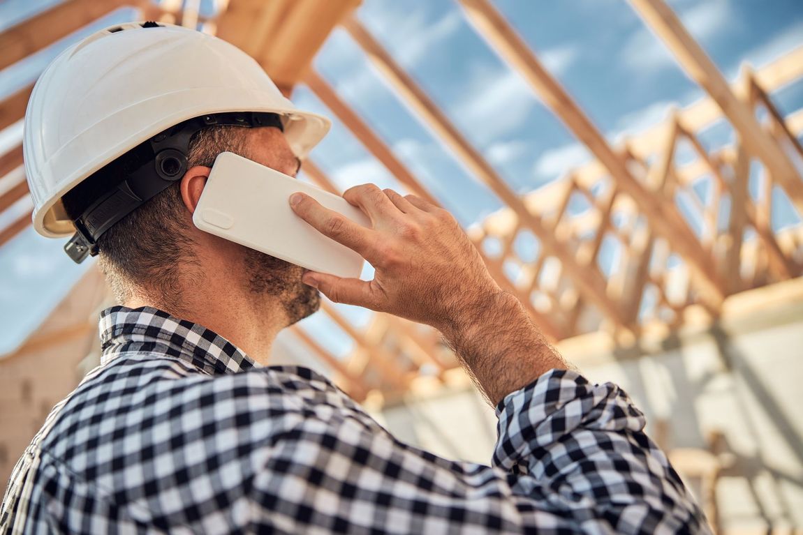 A construction worker is talking on a cell phone at a construction site.