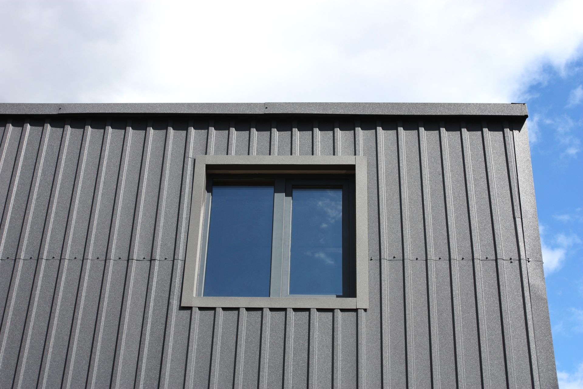 A window on the side of a building with a blue sky in the background.