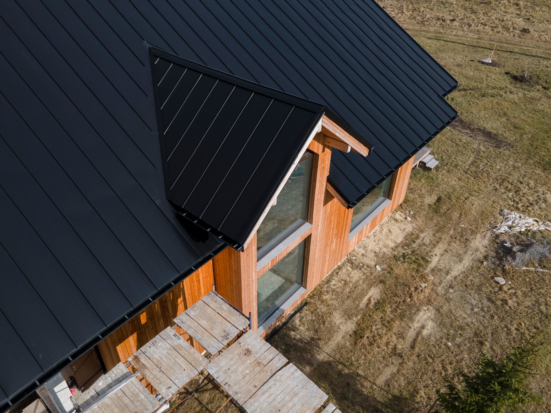 An aerial view of a wooden house with a black roof.