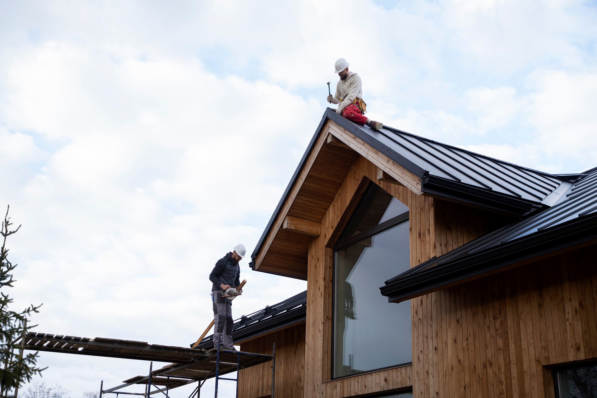 Two men are working on the roof of a wooden house.