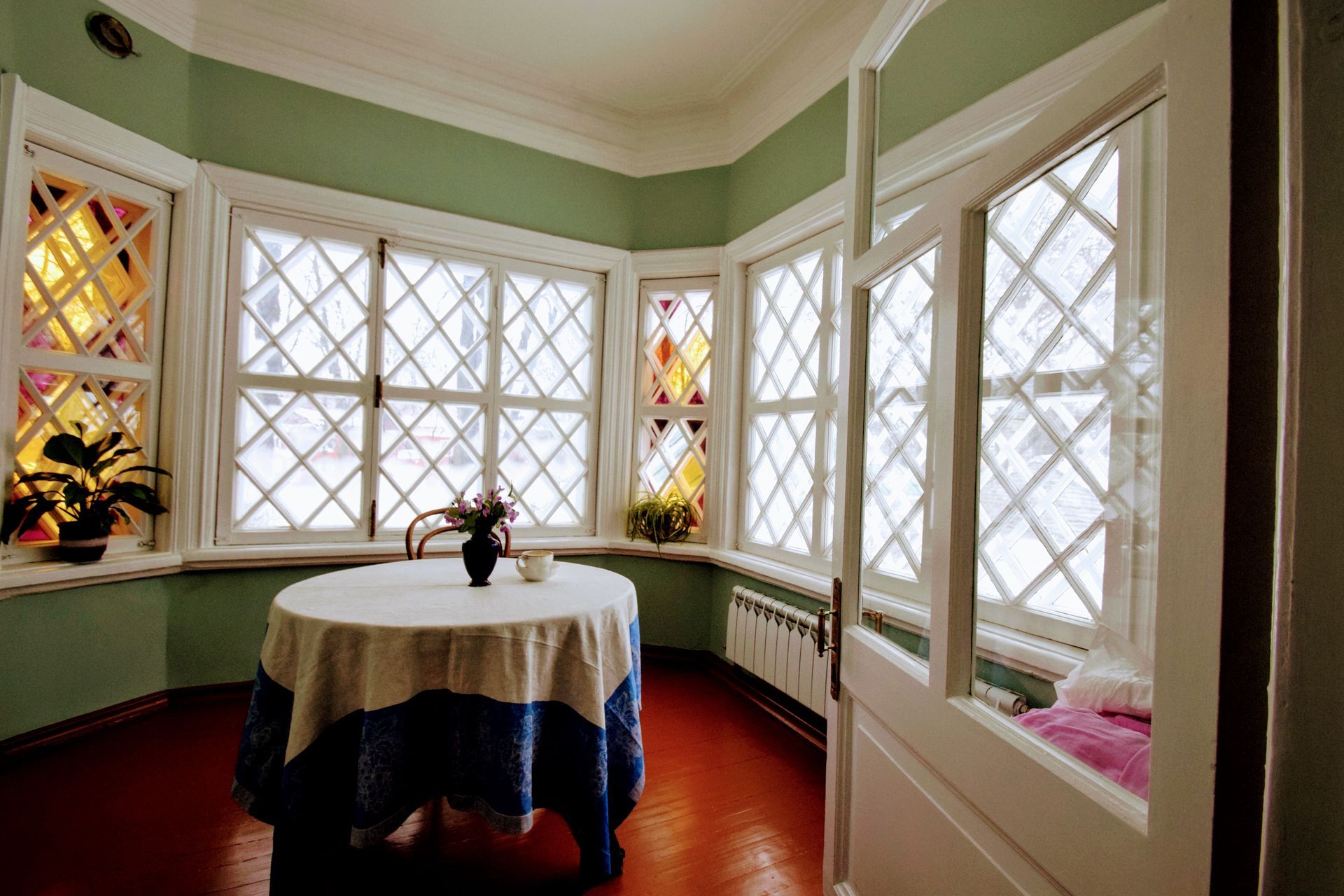 A table with a blue and white tablecloth is in a room with lots of windows.