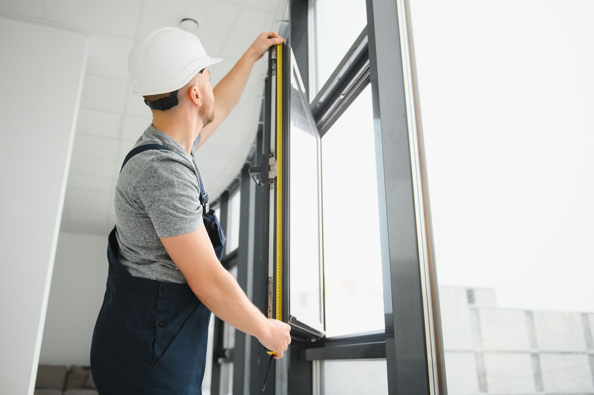 A man is measuring a window with a tape measure.