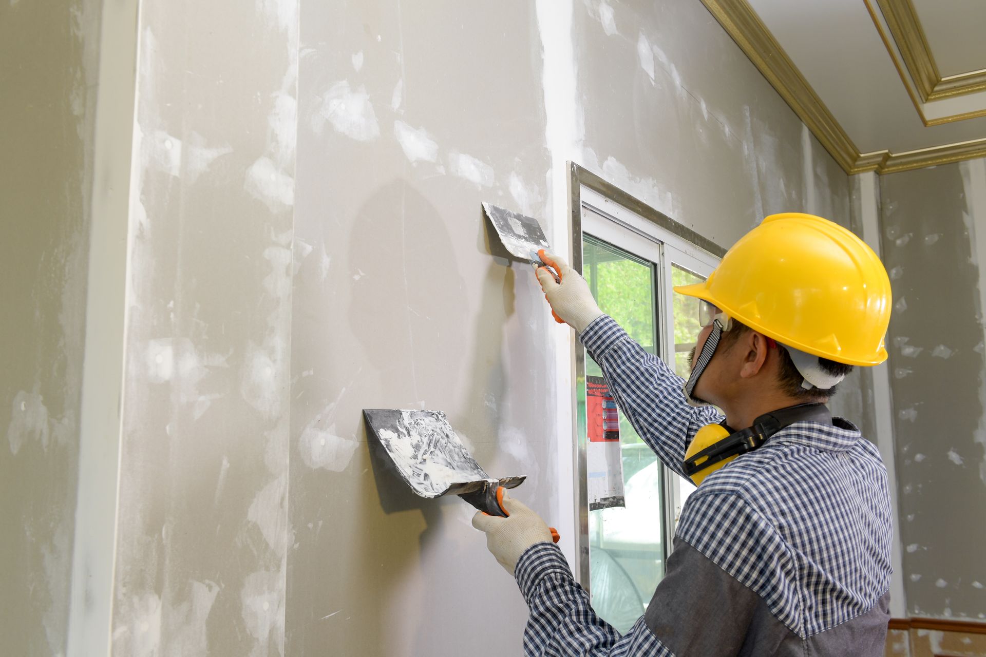 A man is plastering a wall with a spatula.