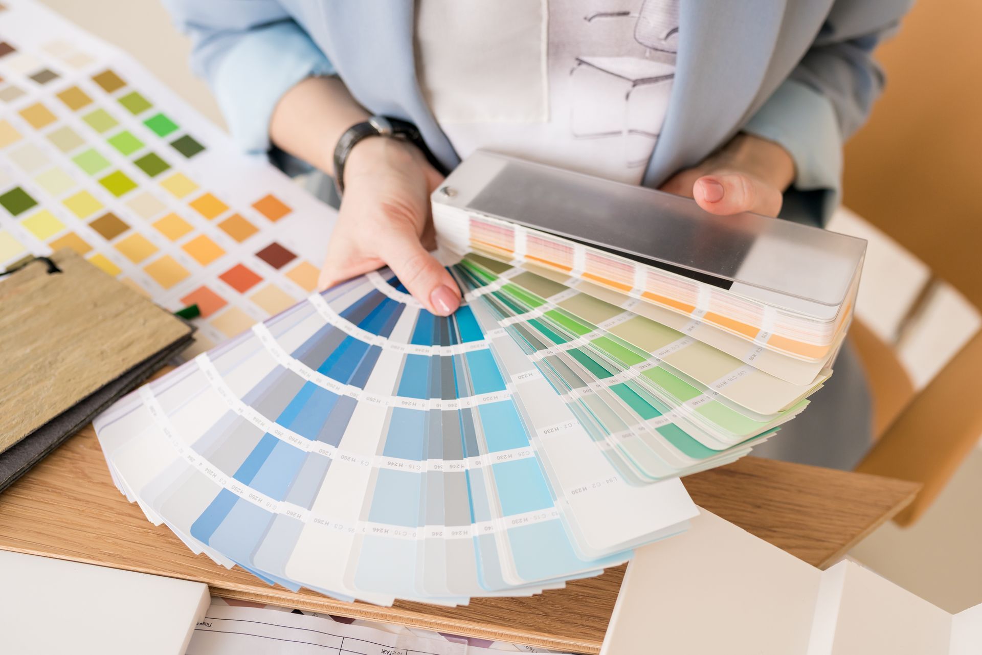 A woman is holding a fan of paint samples in her hands.
