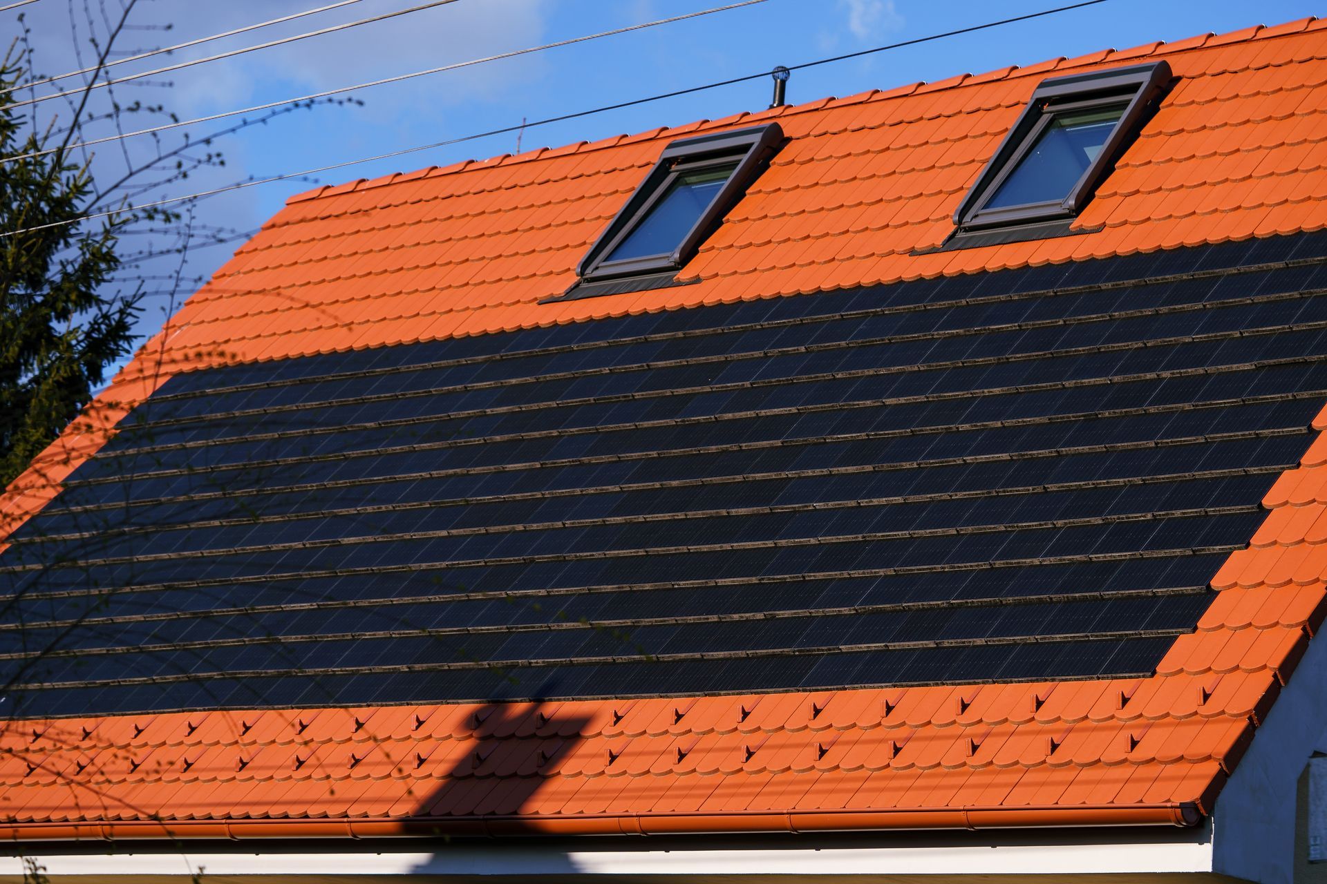 A roof with two skylights and solar panels on it