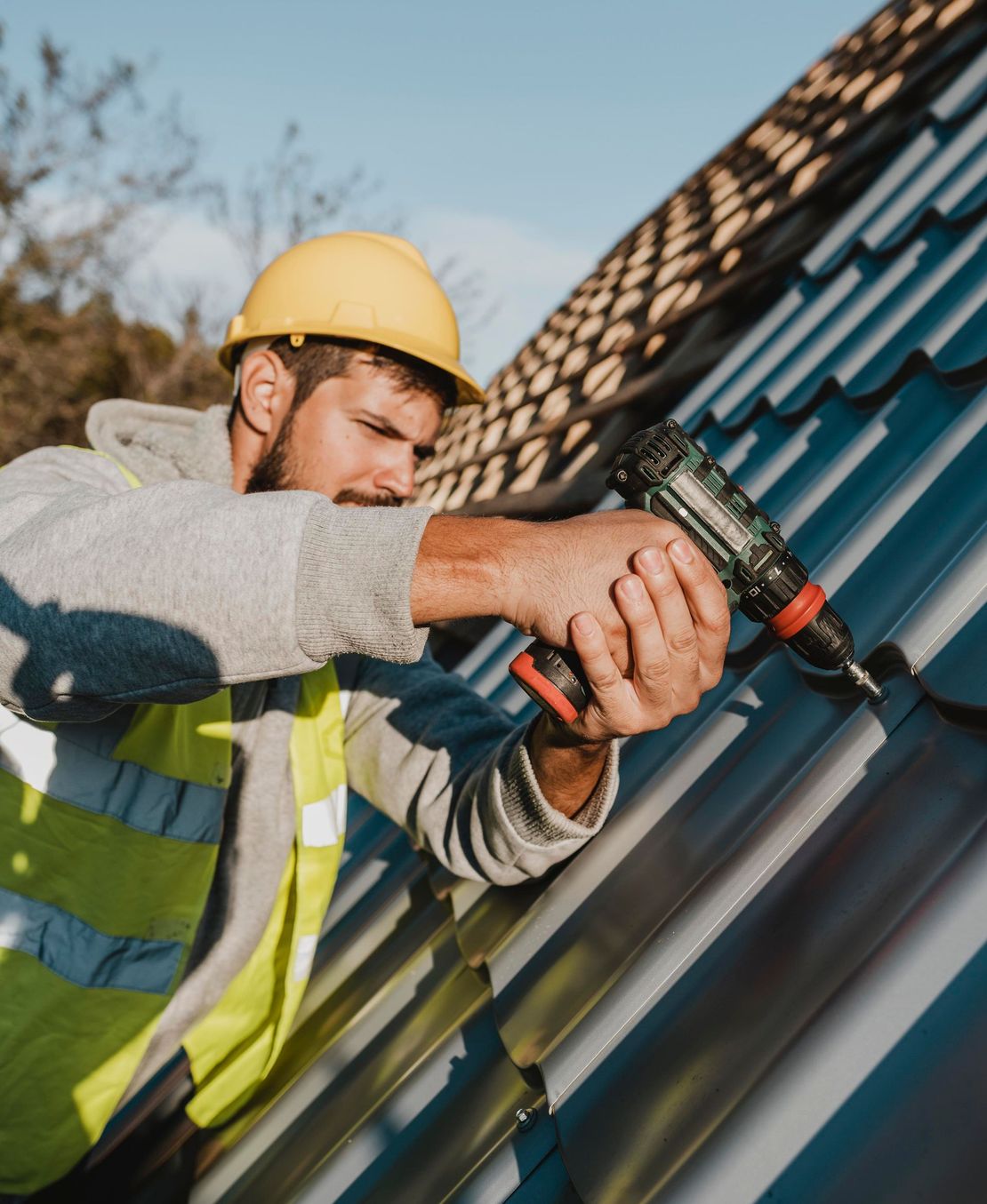 A man is working on a roof with a drill.
