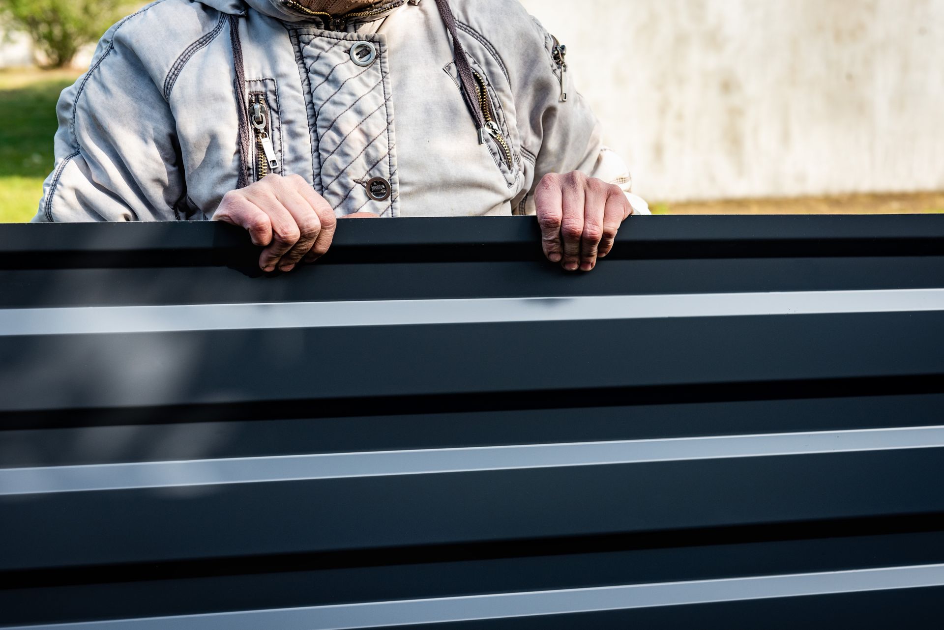 A man is holding a black metal fence with his hands.