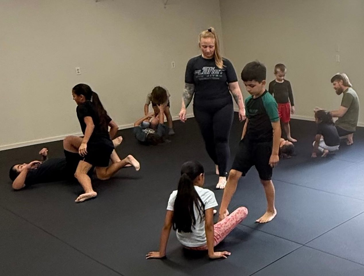 Children practicing Brazilian Jiu-Jitsu with an instructor at 10th Planet Bastrop in Bastrop, Texas