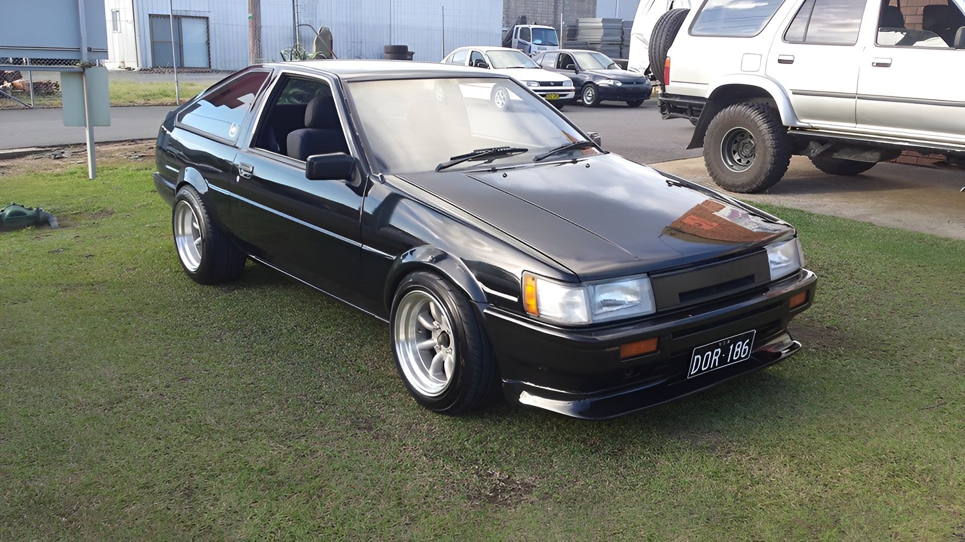 Black Toyota Ae86 Coupe Parked on Grass With Silver Wheels — EFI Evolutions Mechanical Repairs in Grafton, NSW
