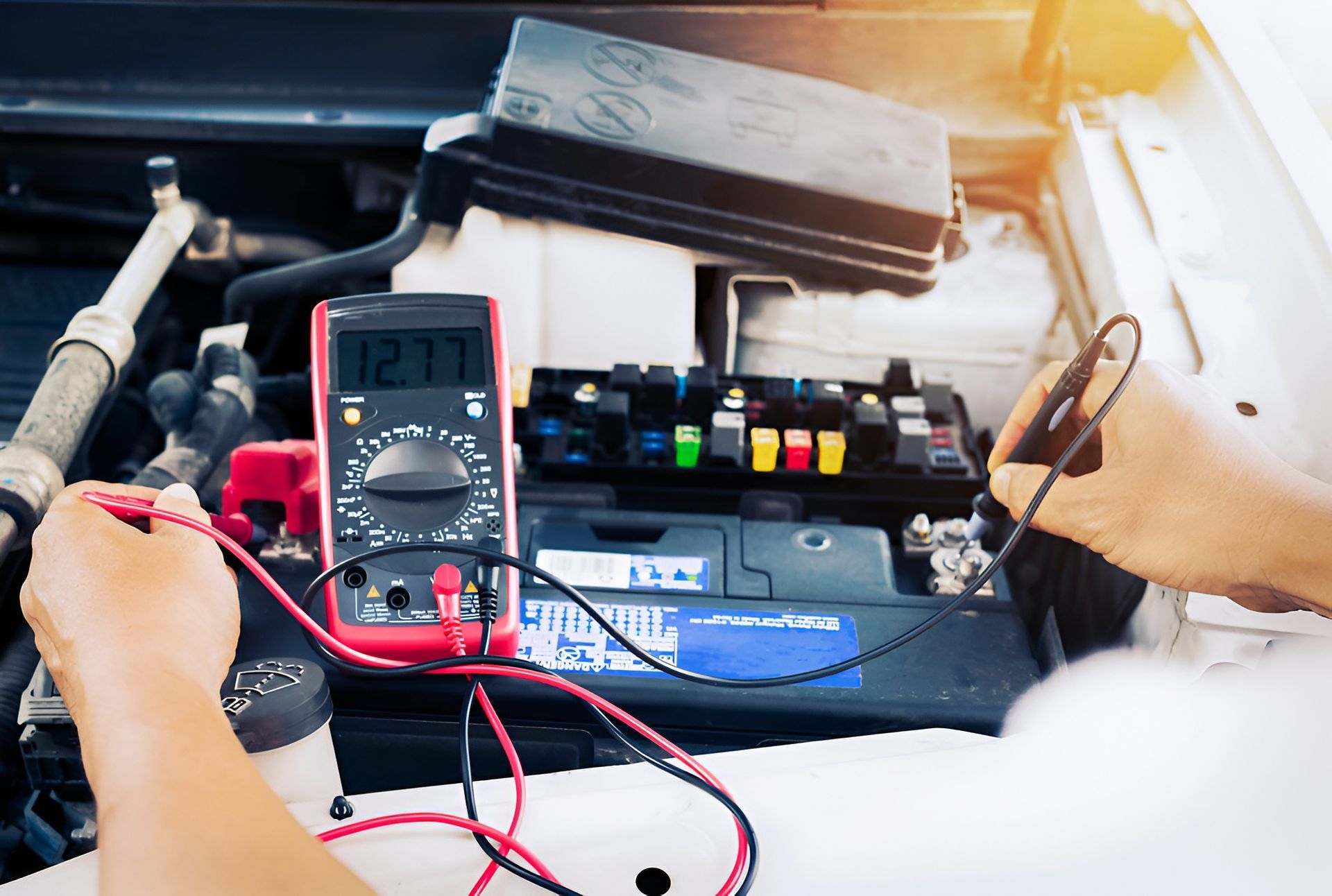 Hands Using a Multimeter to Test a Car Battery — EFI Evolutions Mechanical Repairs in Coffs Harbour, NSW