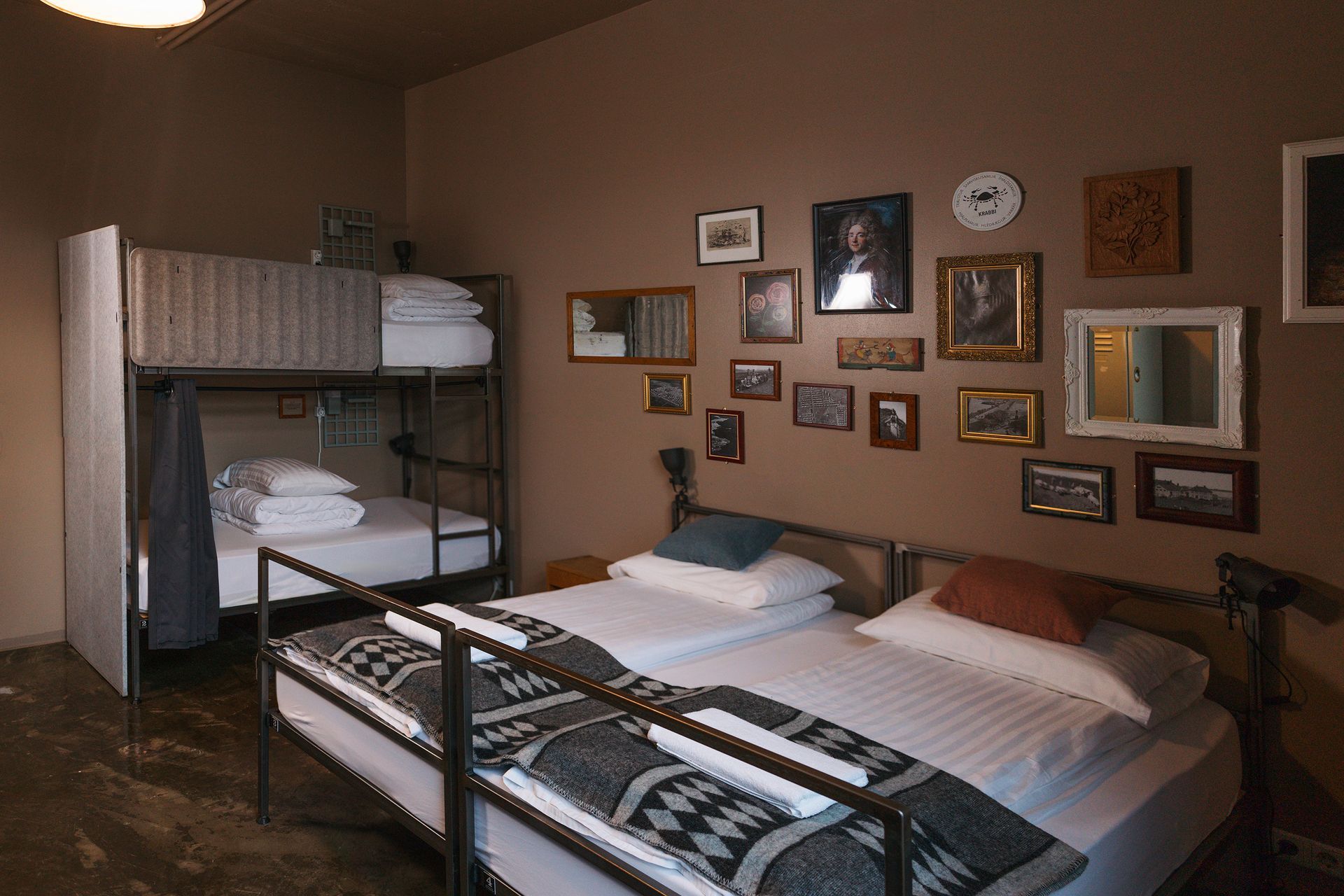 Bedroom with bunk beds, two single beds, and various framed pictures on a brown wall.