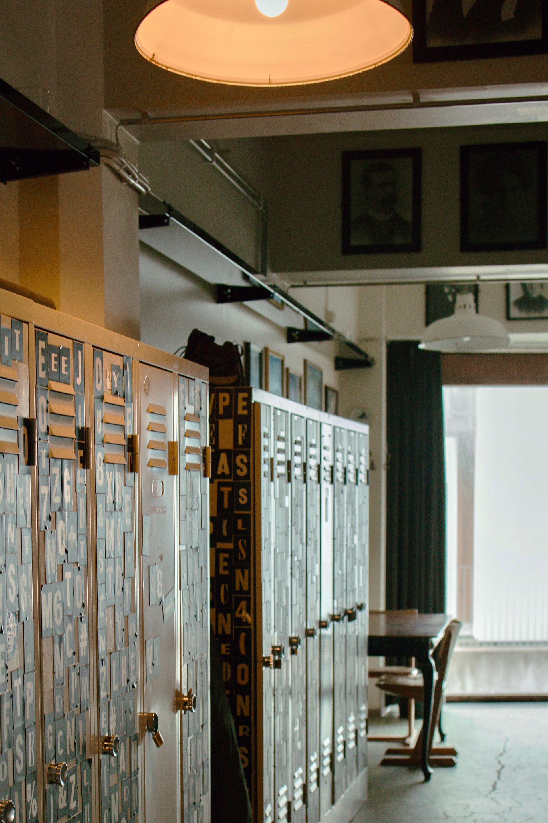 Row of lockers in a room with a light fixture above; a table and window are in the background.