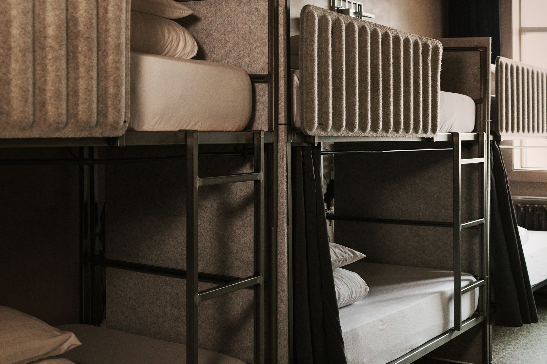 Bunk beds in a room, metallic frames, white bedding, privacy curtains.