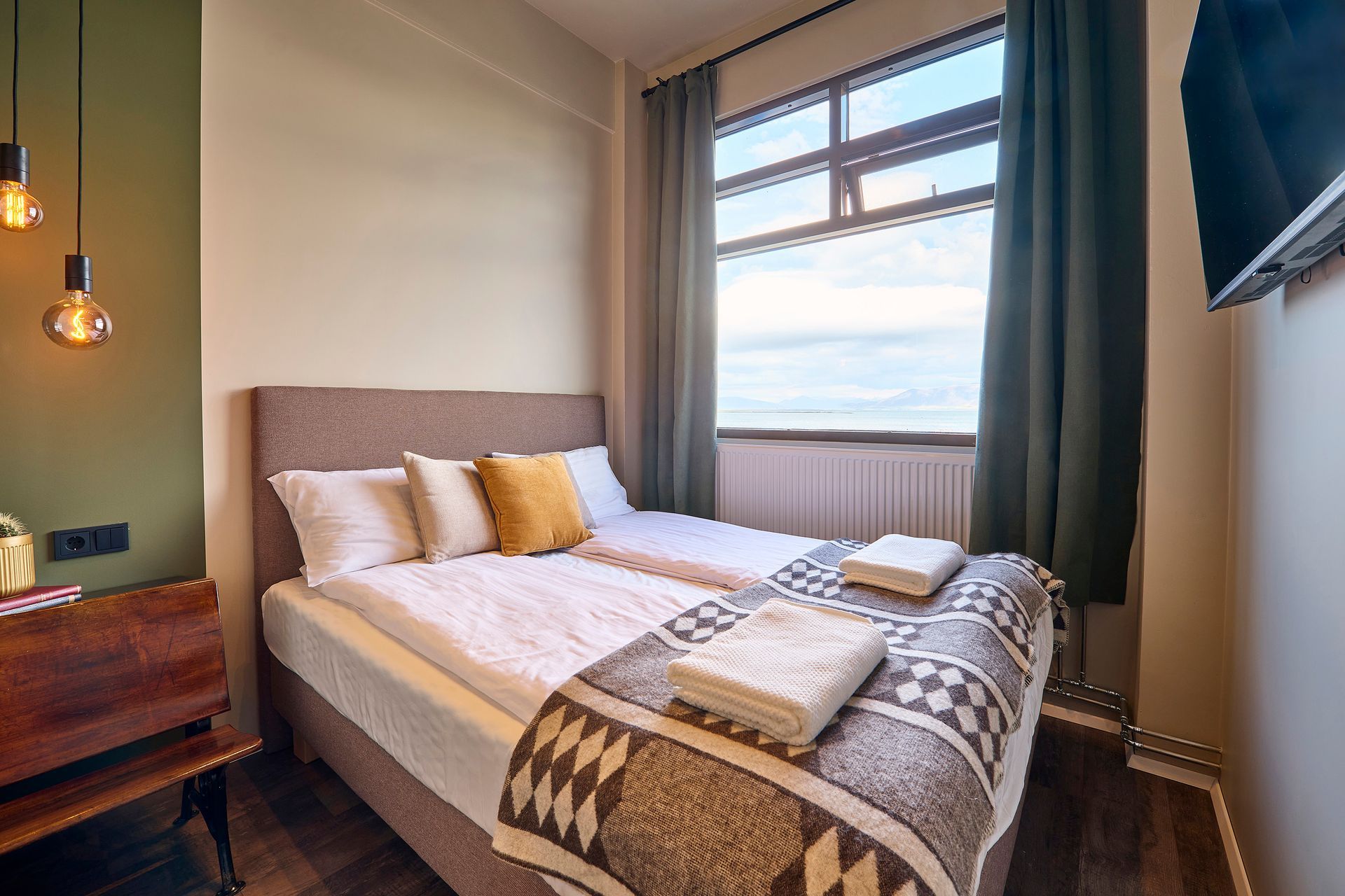 Bedroom with twin beds, window with view, green and brown decor.