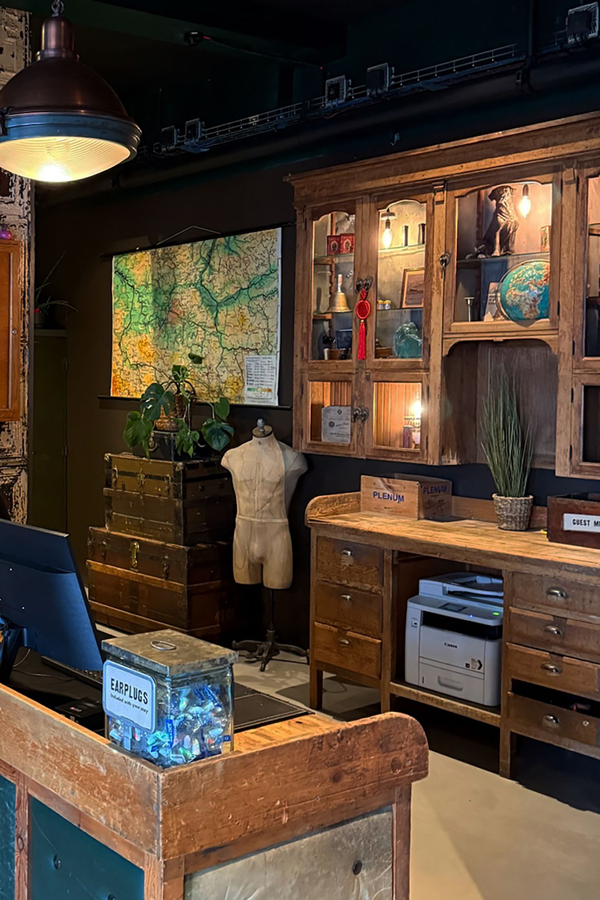 A vintage-style office with wooden furniture, a map on the wall, and a mannequin.