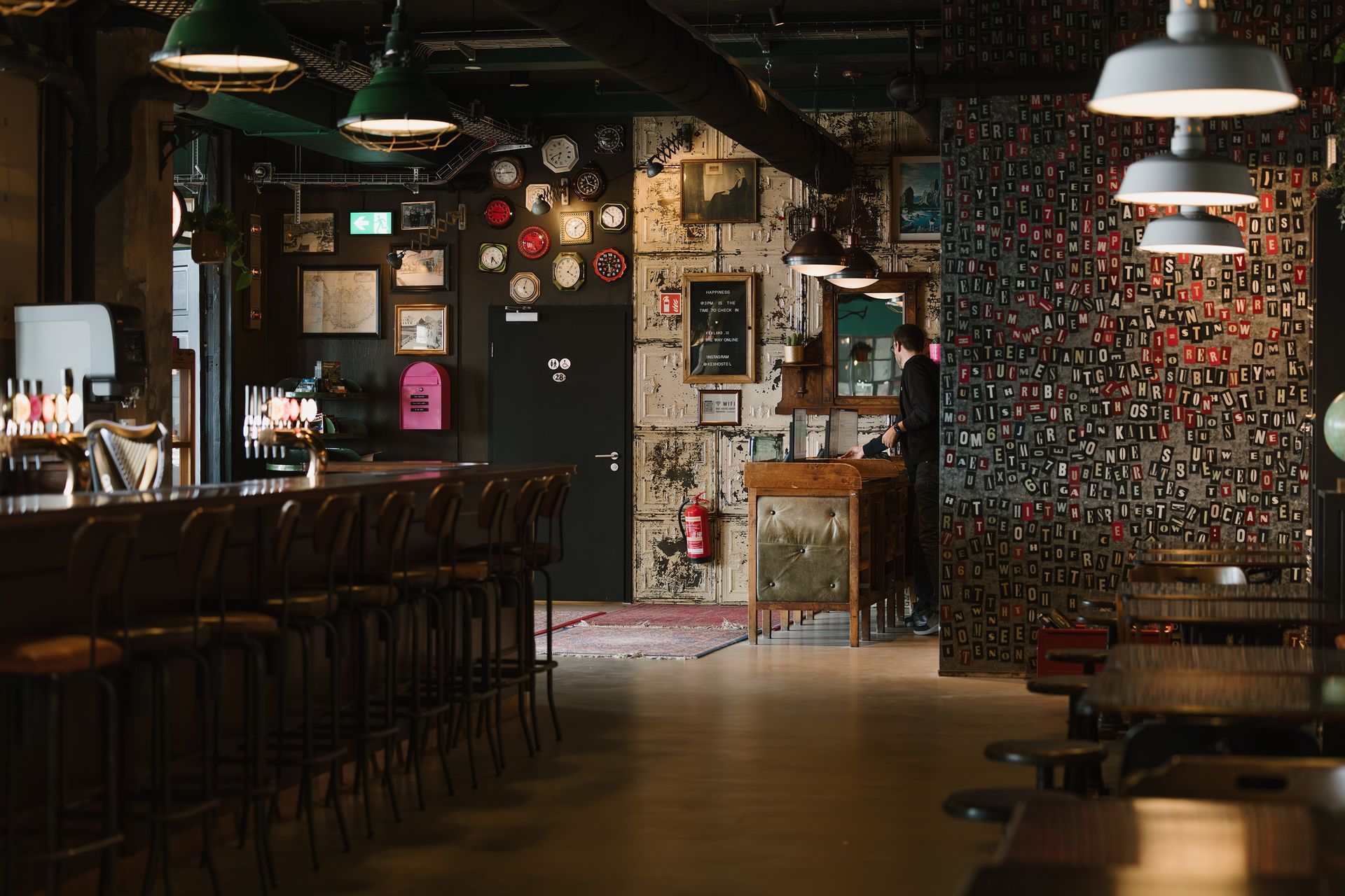 Interior of a dimly lit bar with bar stools, tables, and eclectic wall decor.