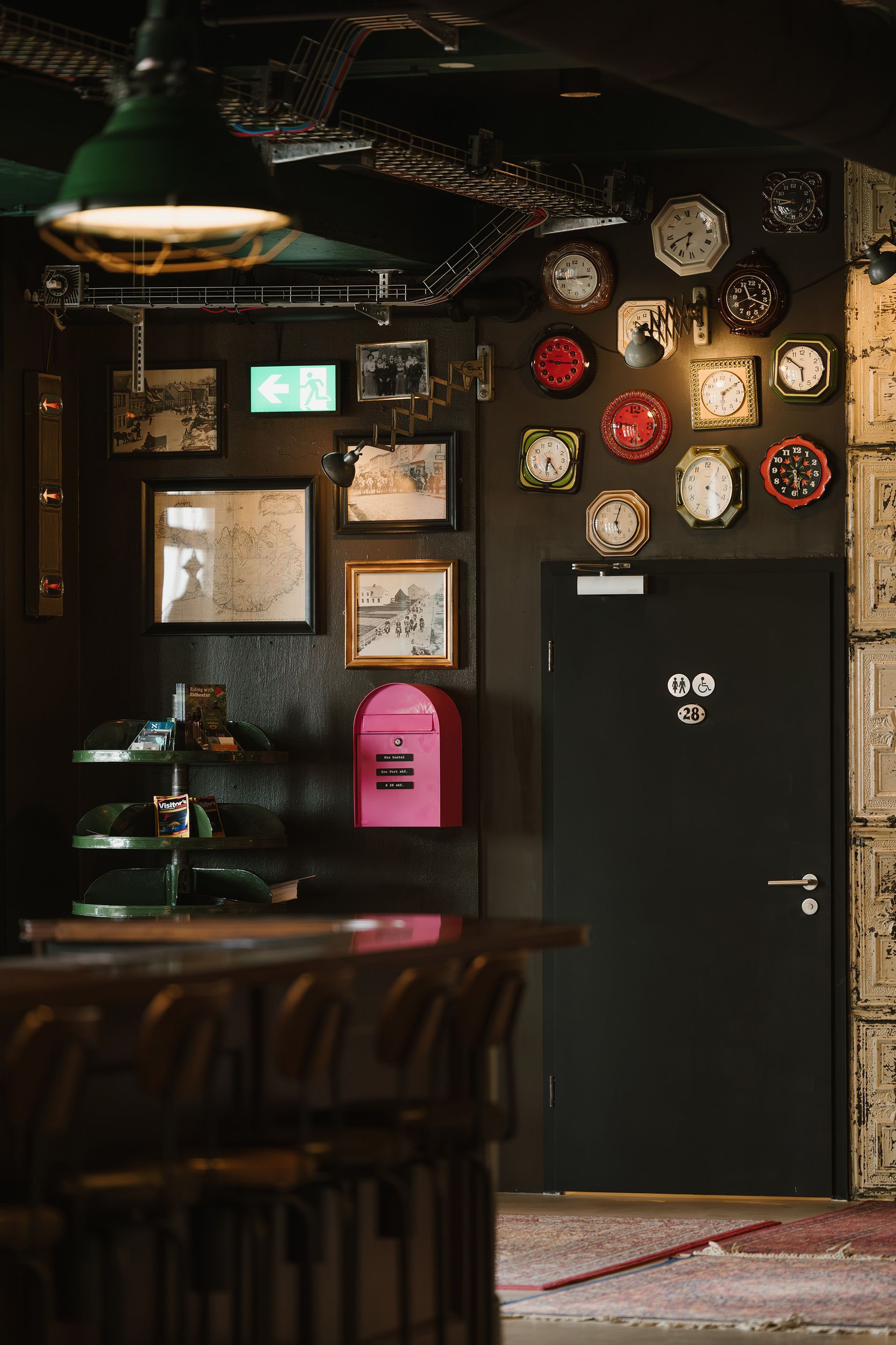 Interior with dark walls, bar, decorative clocks, and a black door.