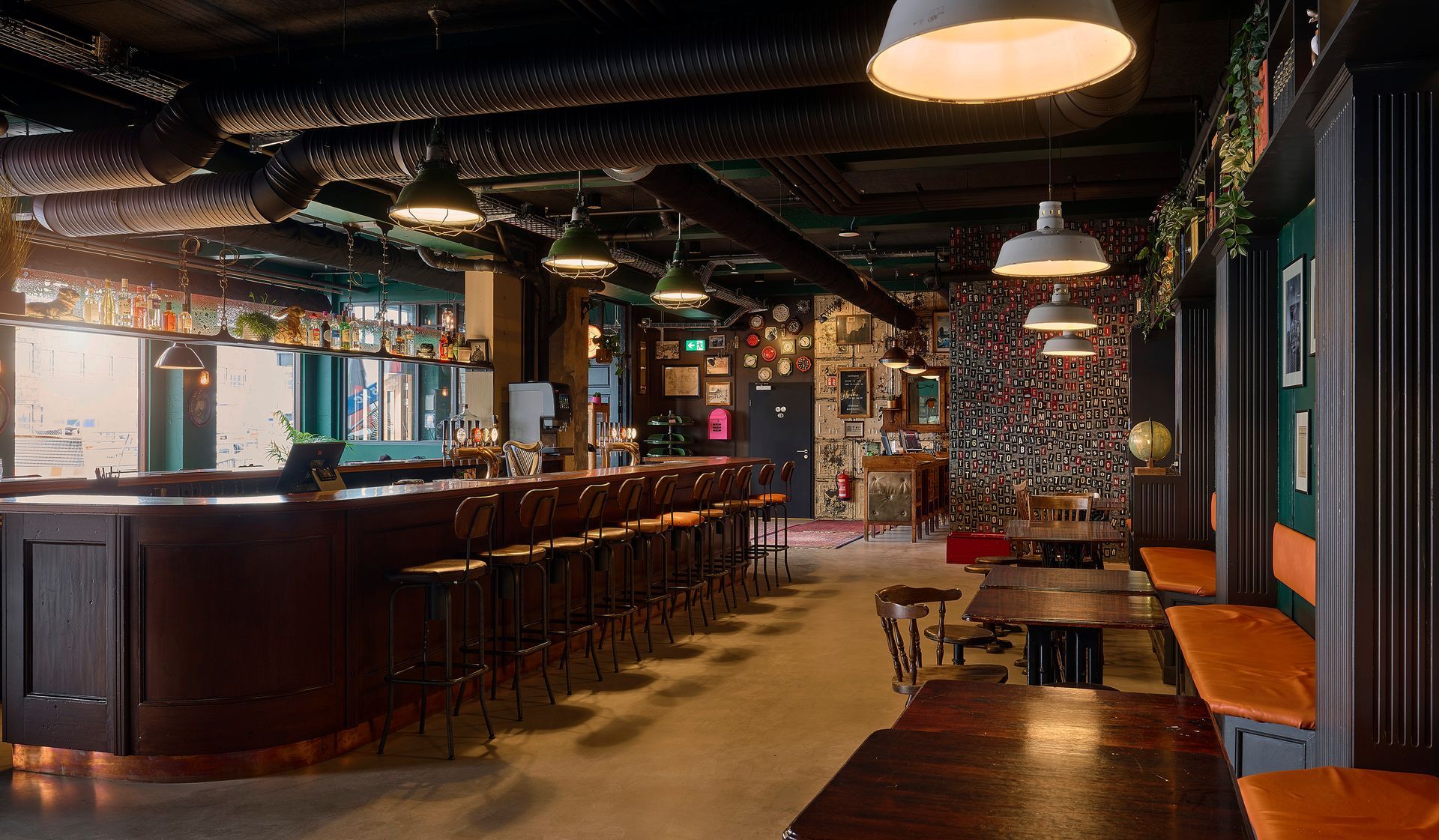 Interior of a pub with a bar, stools, tables, and eclectic decor. Dim lighting and exposed ceiling.