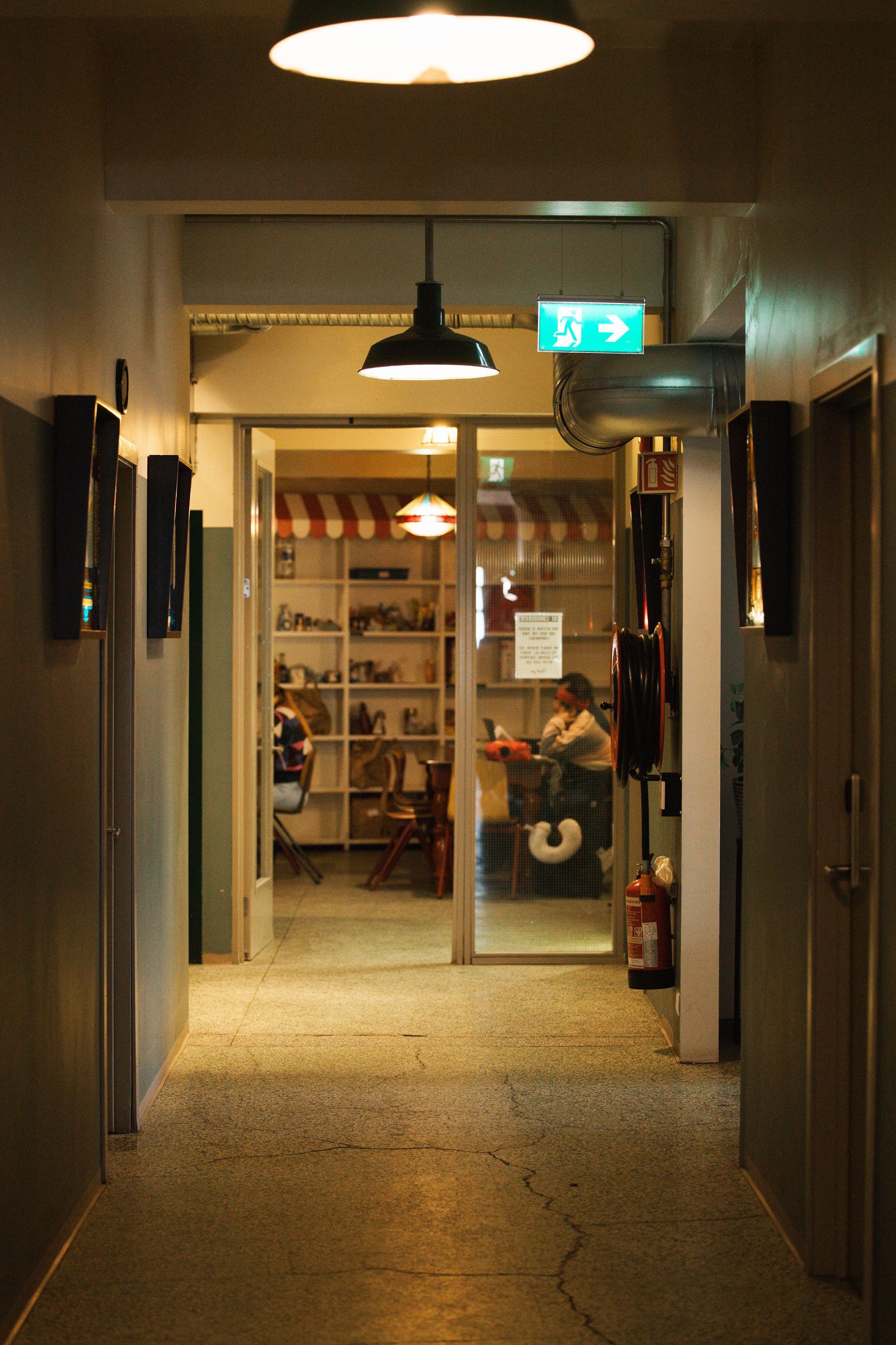 Hallway leading to a glass door, with lights and shelves visible.