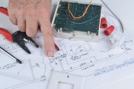 Picture of a electrical handyman services repair provider pointing at electrical drawings where electrical tools are sitting.