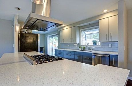 Picture of a kitchen remodeled and renovated by Richmond Construction. The kitchen has quartz counter tops and brown cabinets.