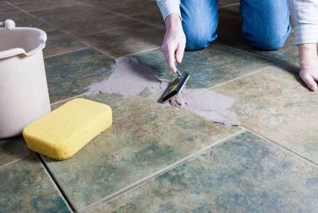 Tile Installation and  repair - Handyman working to spread mortar to lay tiles on the floor using a grouting and tile tool.