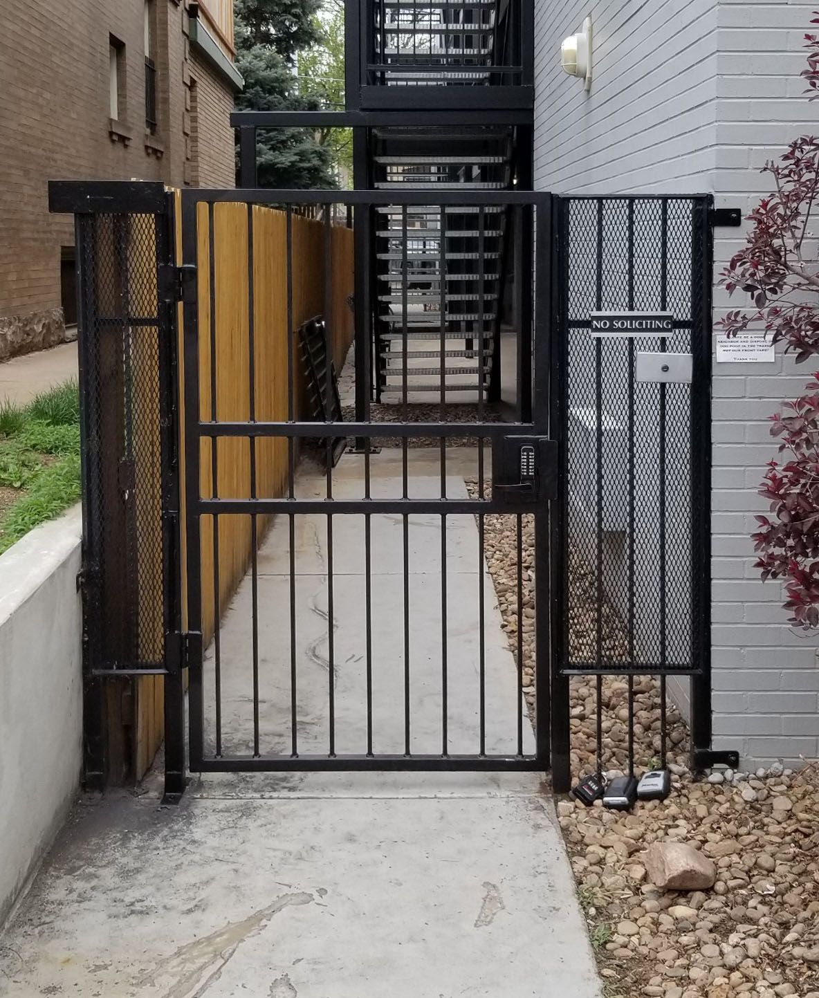 A metal gate leading to a walkway with a staircase in the background