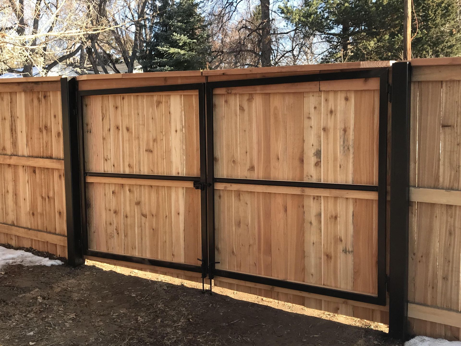 A wooden fence with a metal gate attached to it.