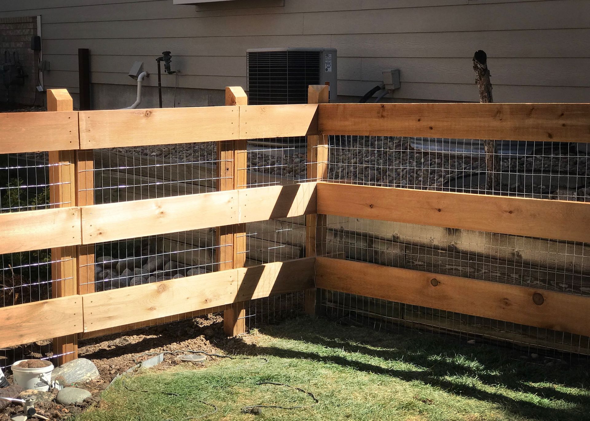 A wooden fence with wire mesh is in the backyard of a house