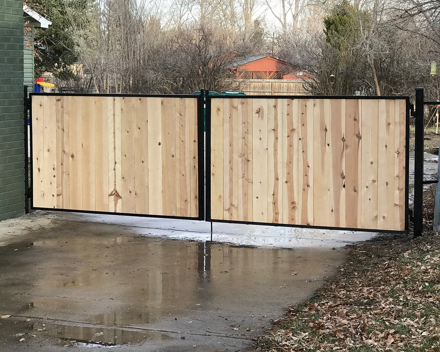 A wooden gate is sitting in the middle of a driveway.