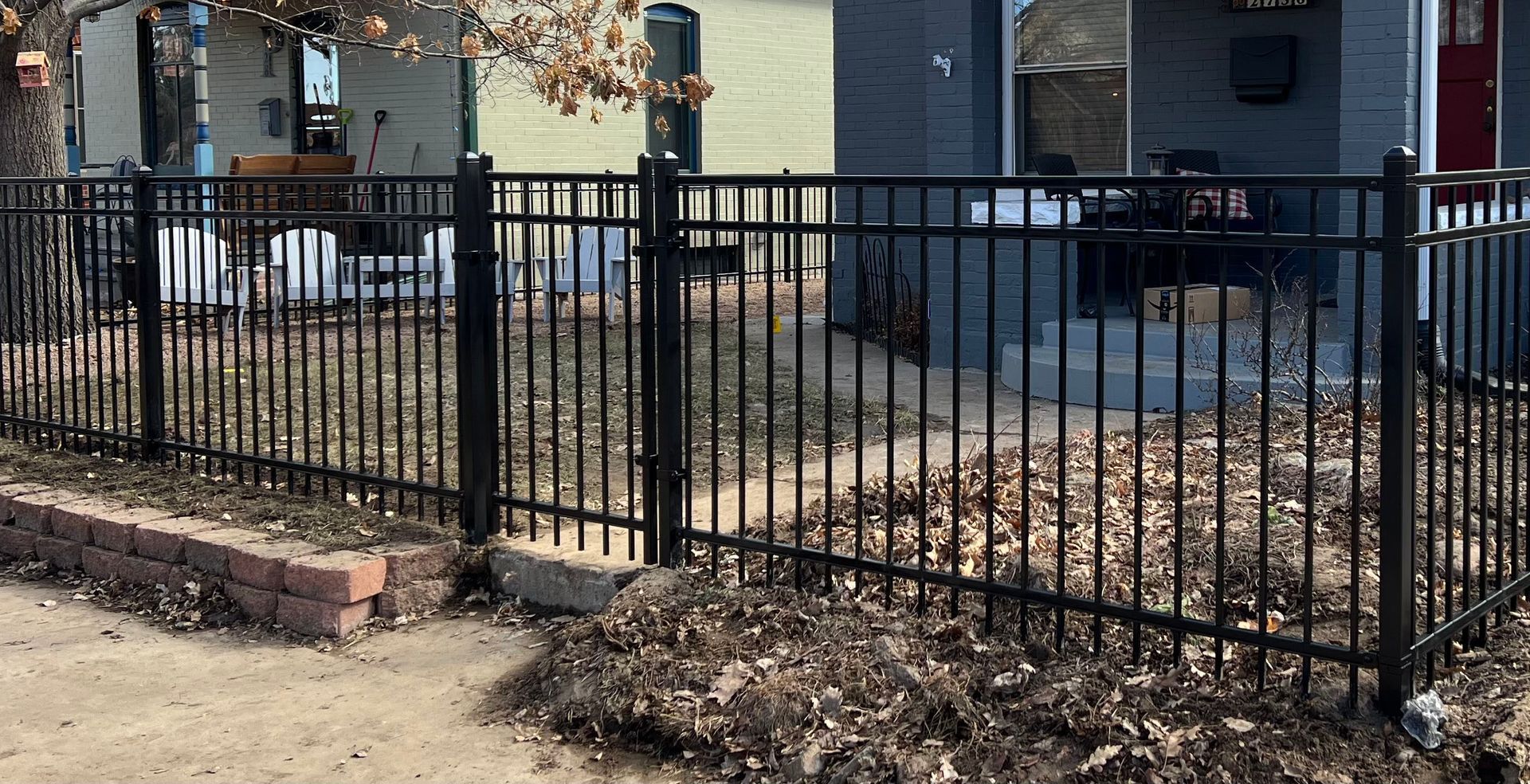 A black wrought iron fence surrounds a yard in front of a house.