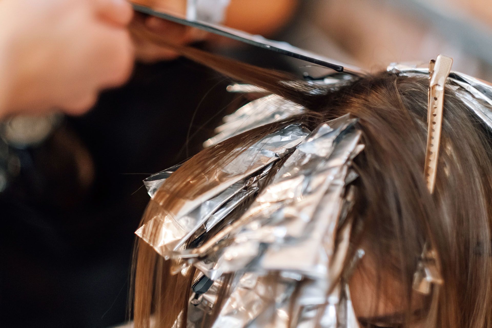 Hairdresser applying hair dye with foil.