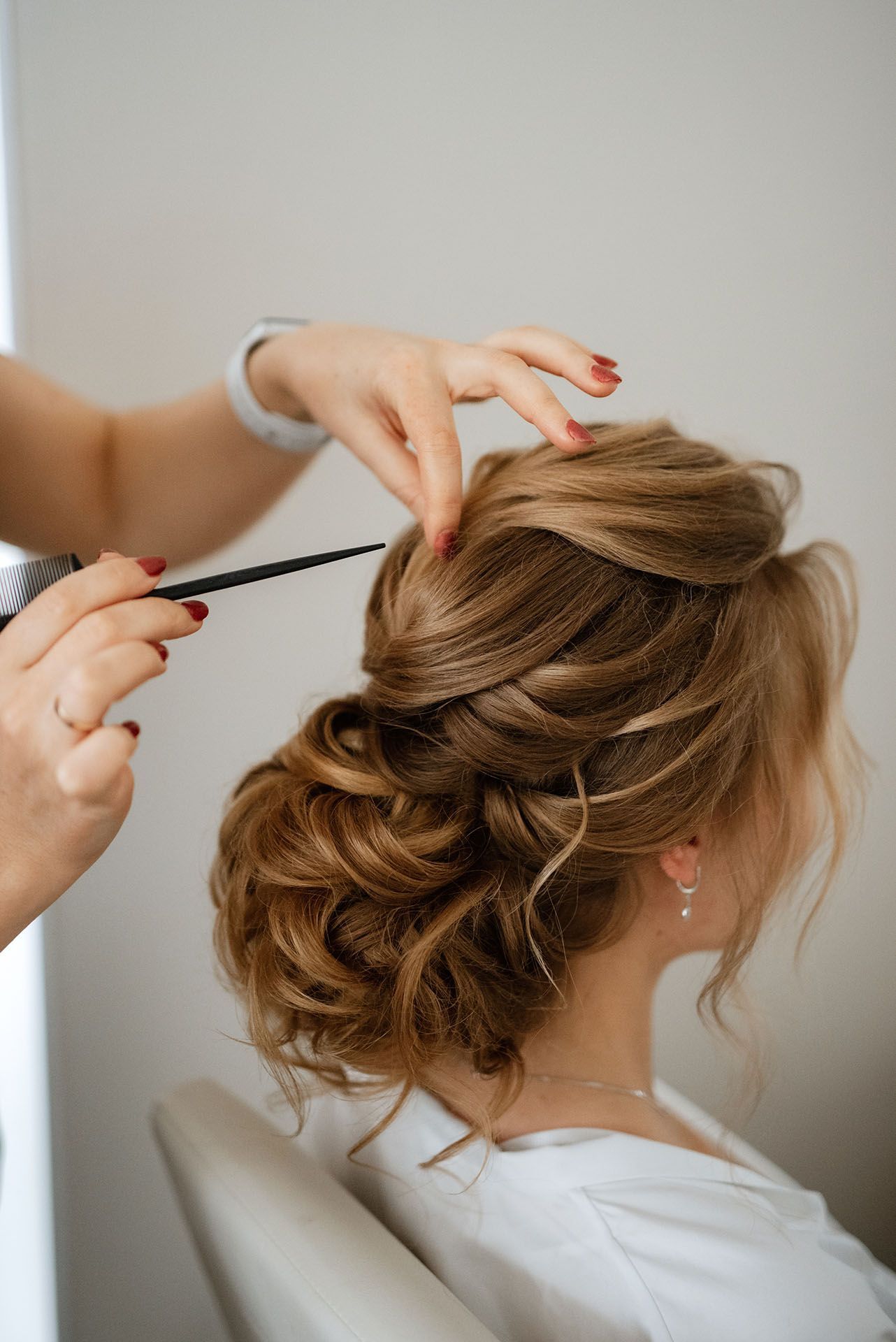 A person's hair being styled into an updo by a hairstylist.