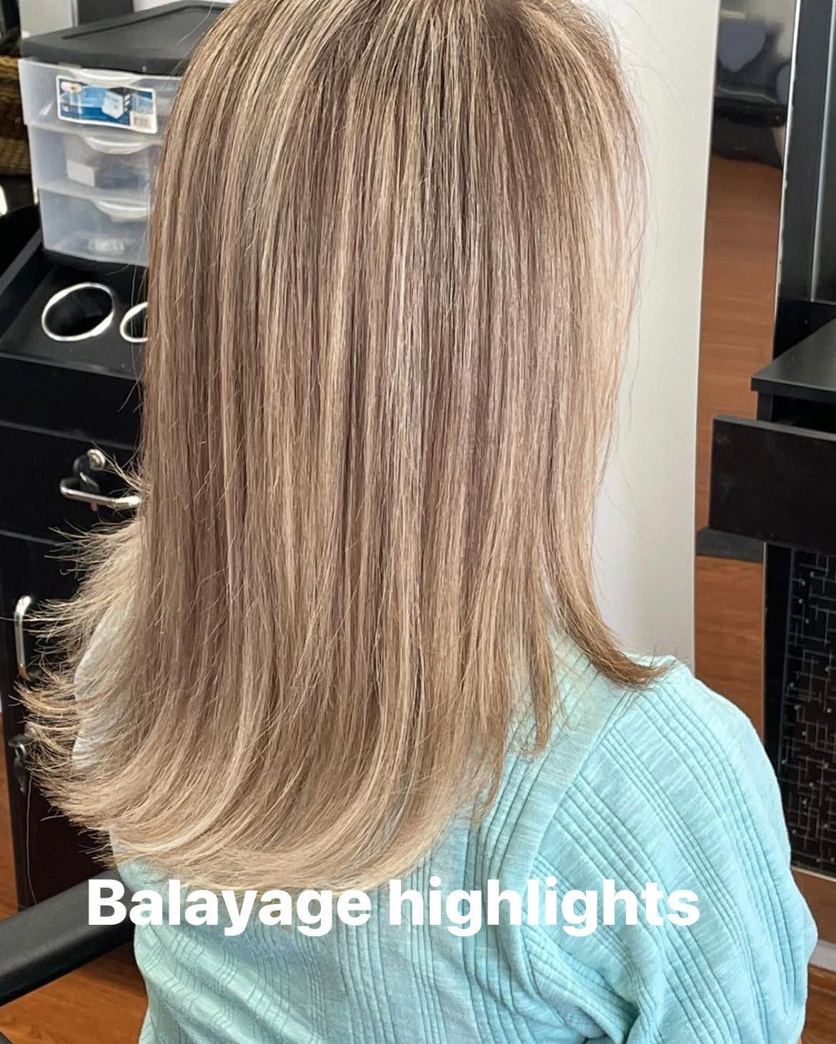 Woman with layered, light brown hair with balayage highlights.