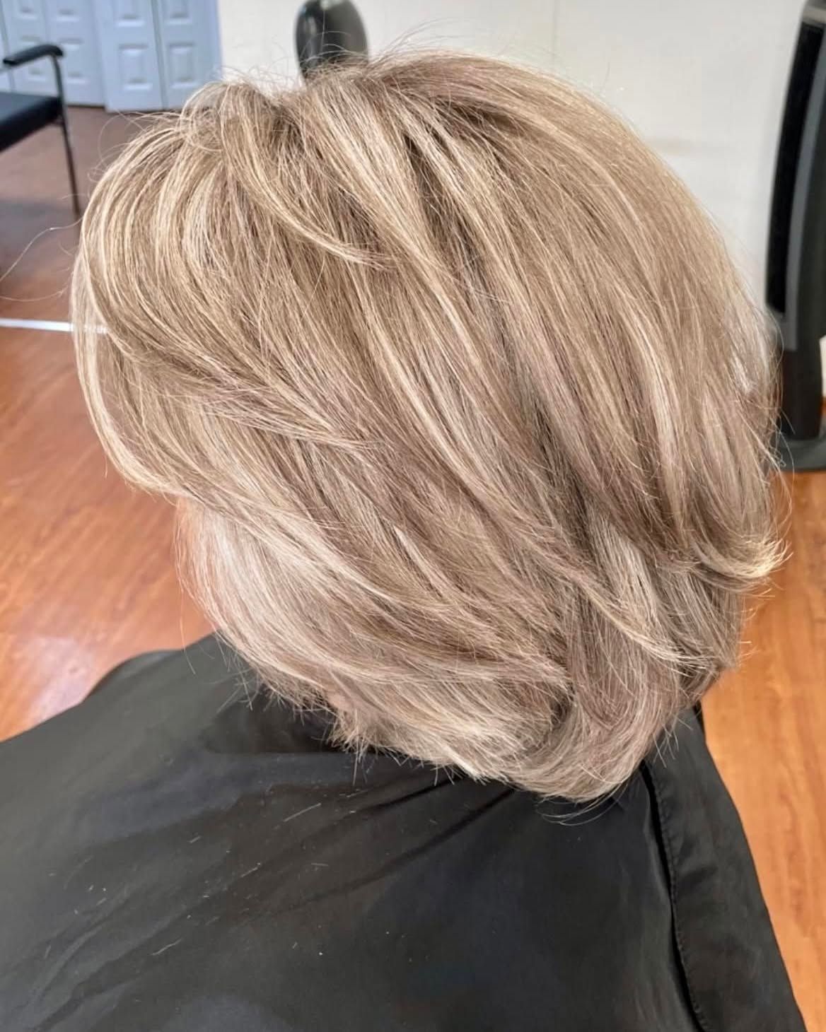 Woman with short layered, ash brown hair, highlighted with blonde.