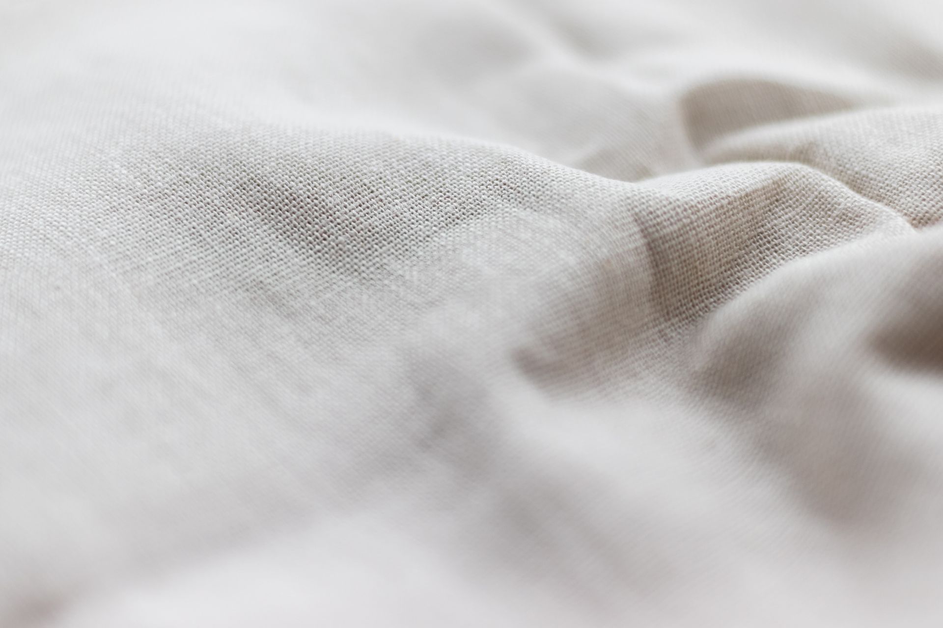 An up-close image of natural linen fabric with a slight crumple to the right