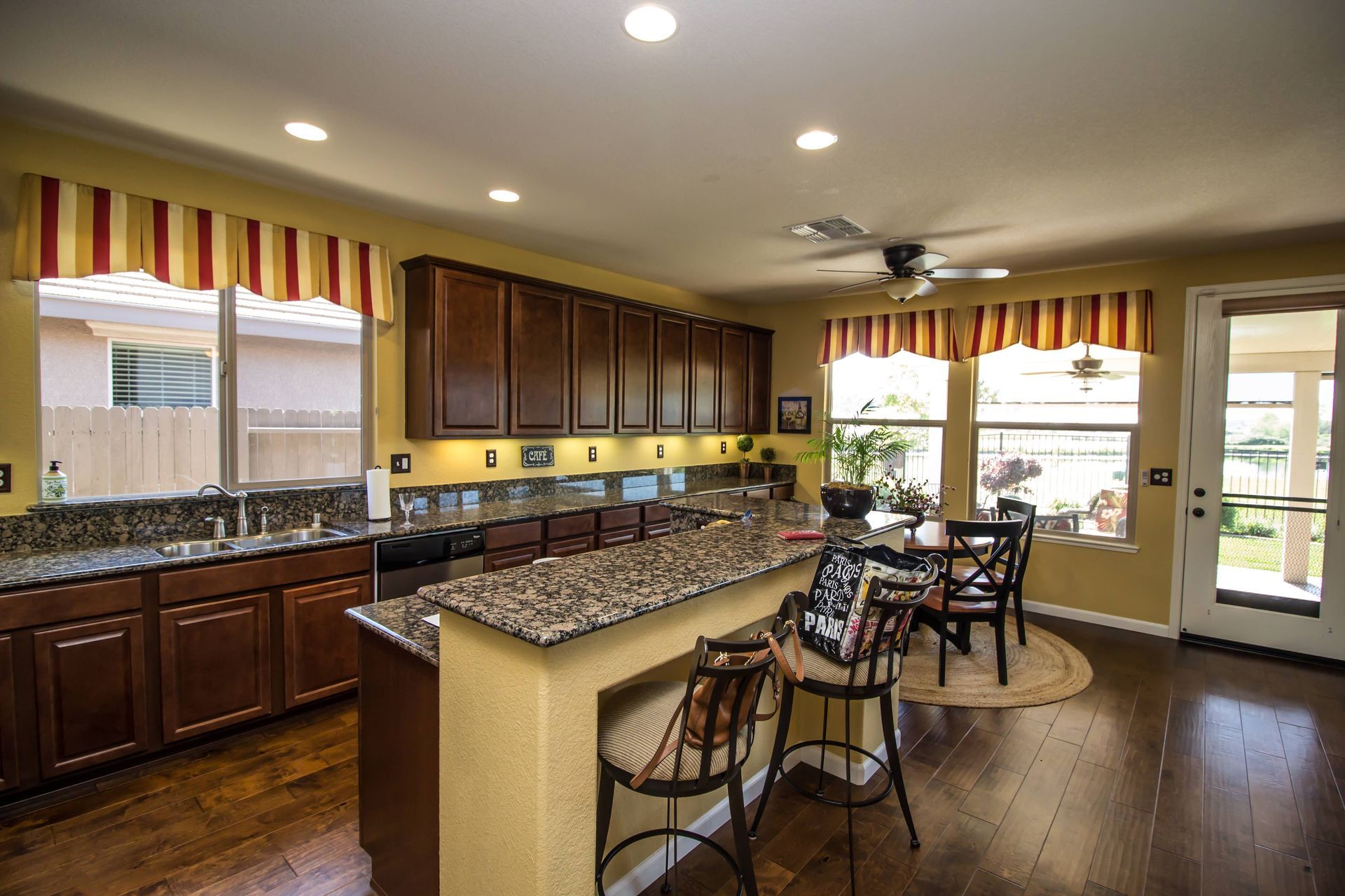 A contemporary kitchen featuring a few windows with custom valances, creating a warm atmosphere  nea