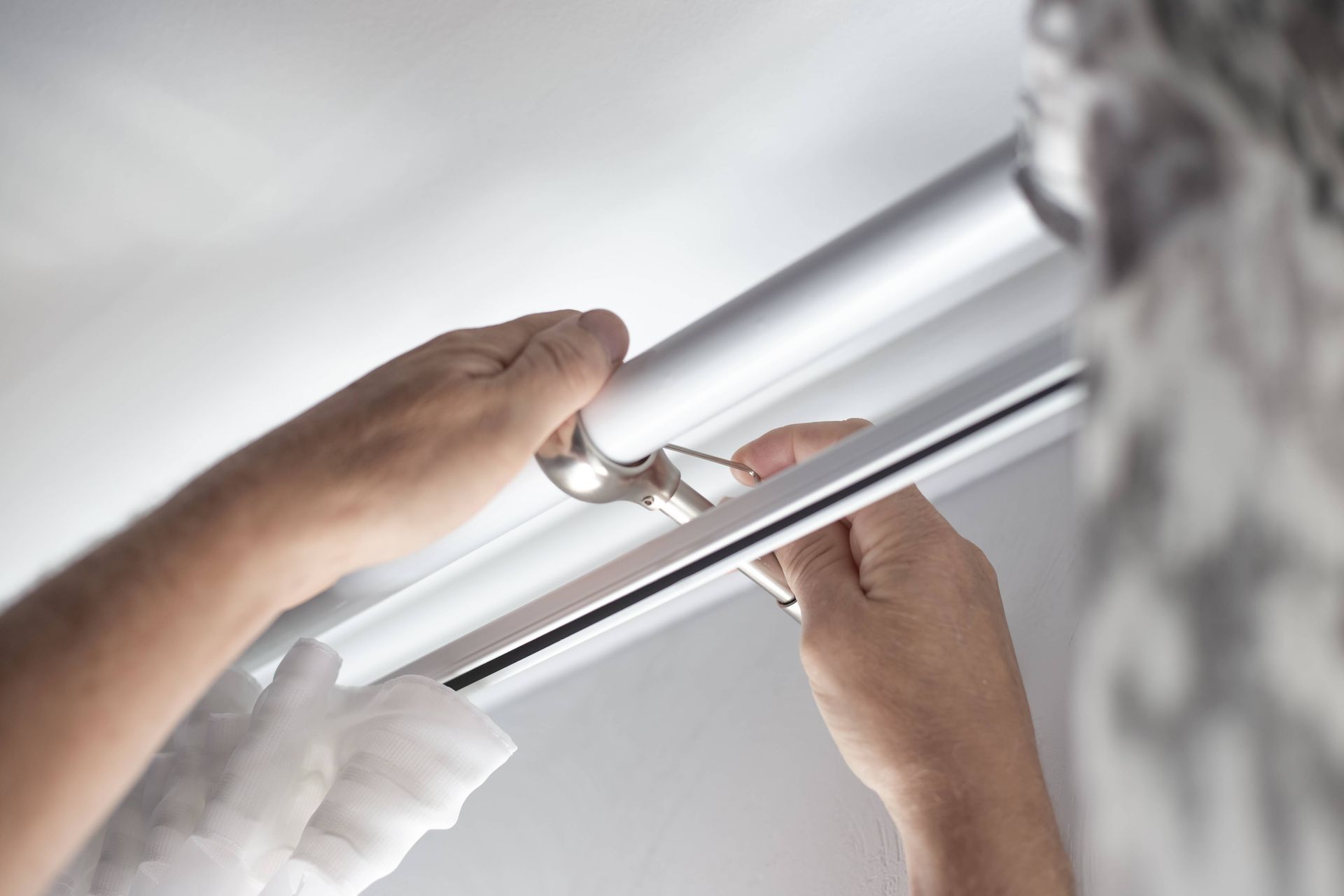 Drapery professional installing a curtain rod to a homeowner's wall to hang their soft window treatments near Huntington, WV