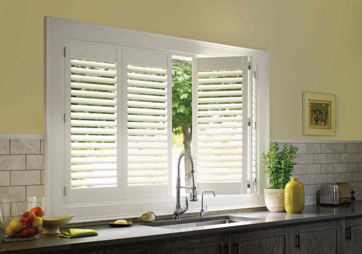 Hunter Douglas vinyl window shutters slightly open on a kitchen window above the sink at Curtain Concepts near Huntington, WV