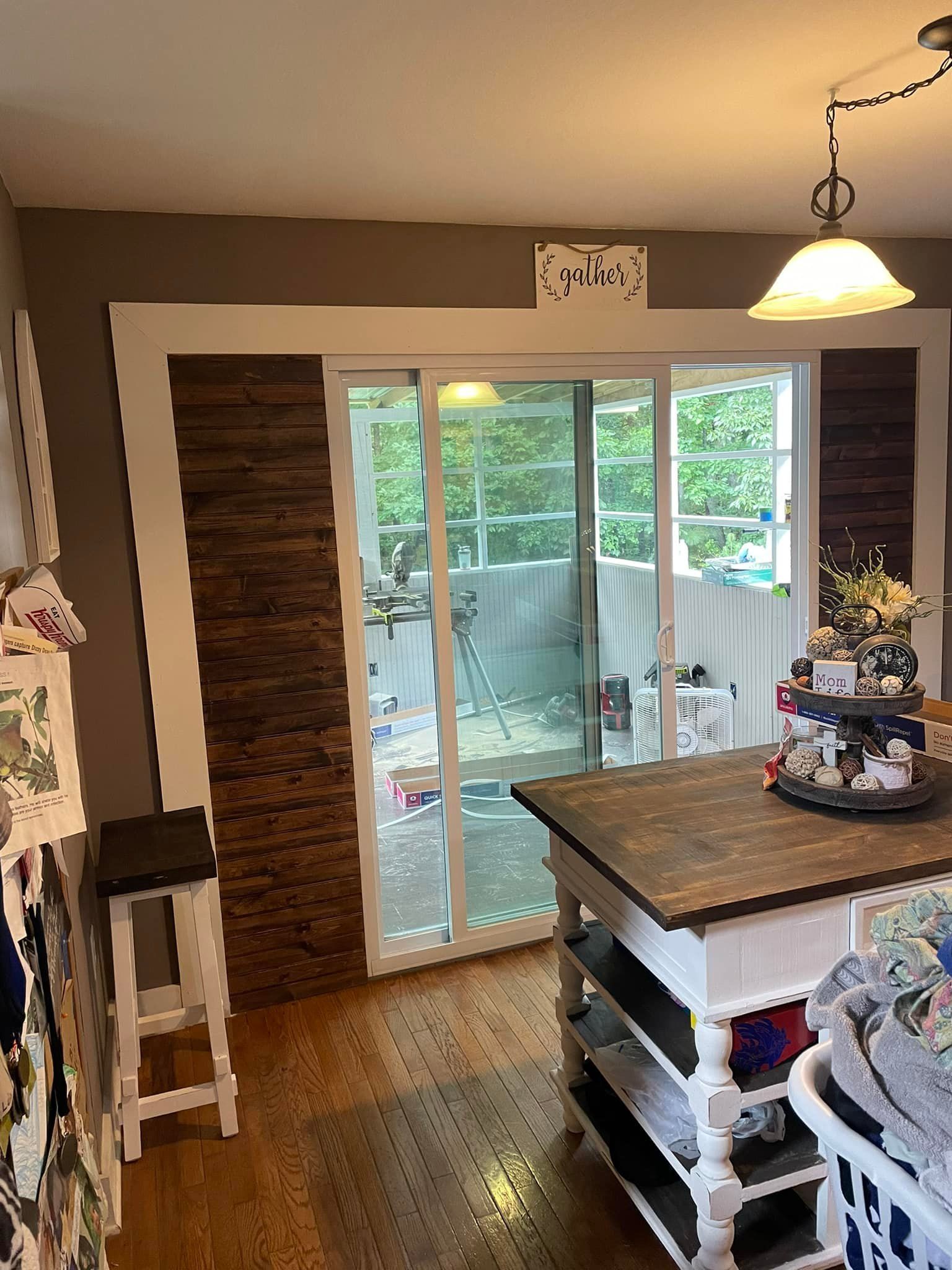 Interior kitchen with a sliding glass door, island, and wood paneling.