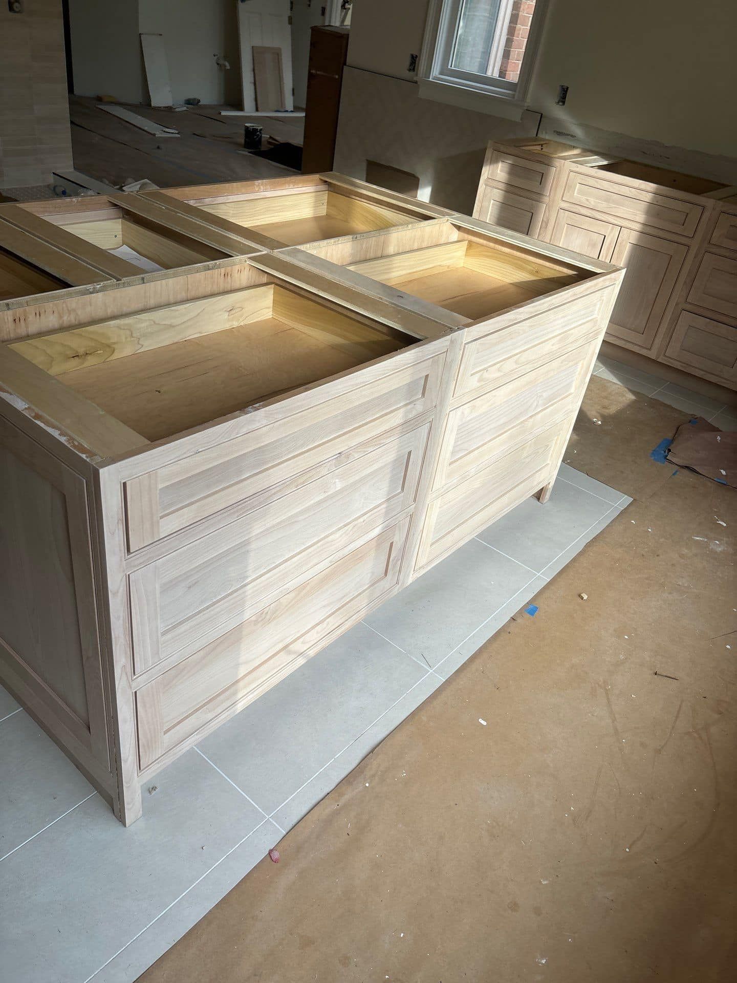 Unfinished light wood kitchen island base in a room under construction.