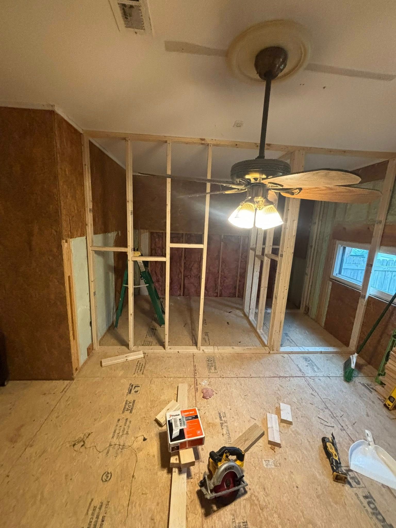 Construction site: Interior room with wooden framing. Power tools on floor, ceiling fan.