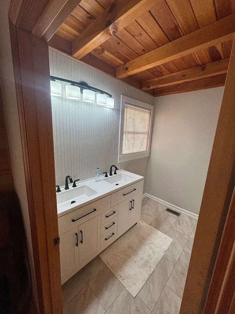Bathroom with white vanity, black fixtures, and wood ceiling.