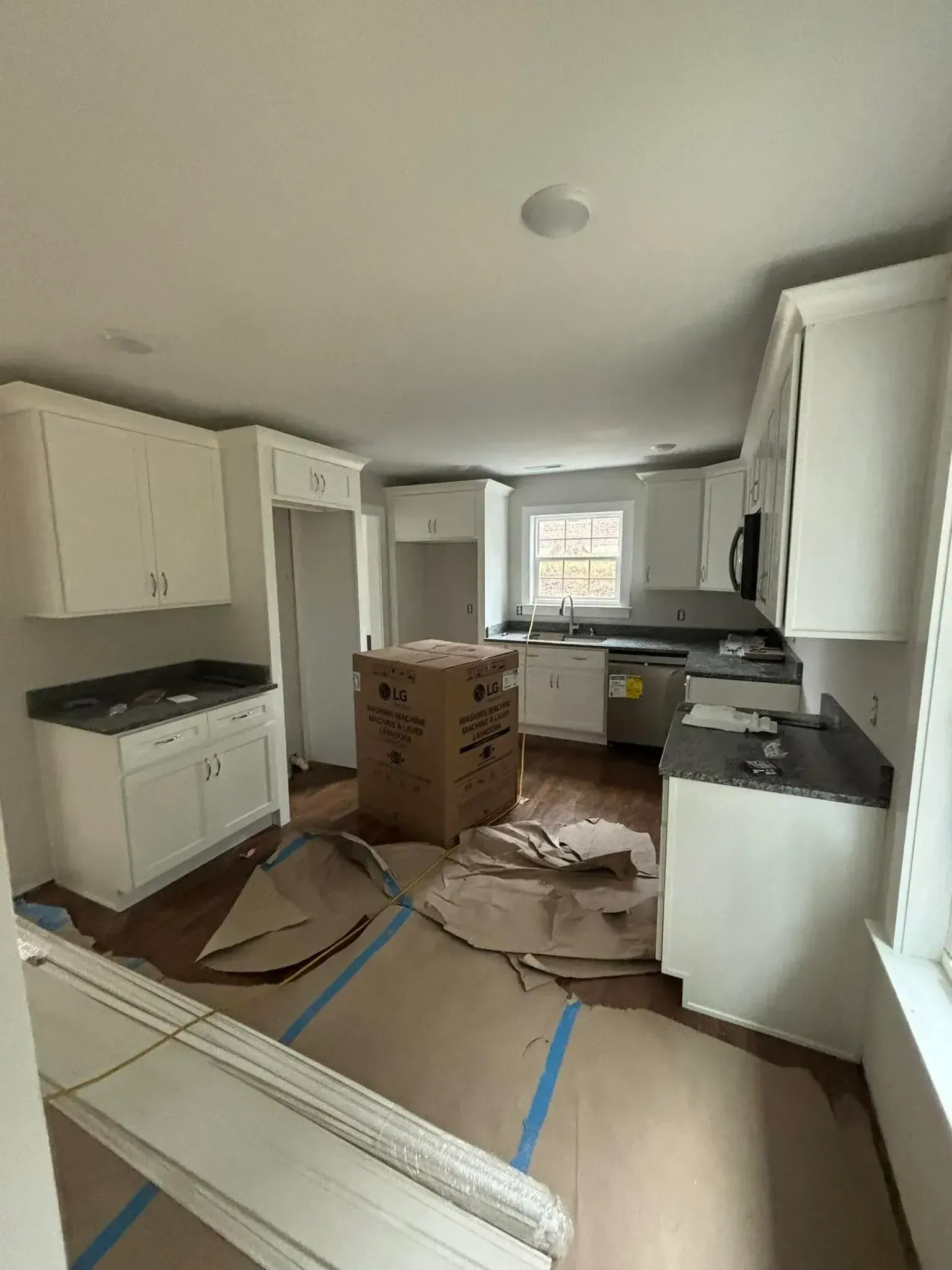 Newly renovated kitchen with white cabinets, dark countertops, and large central box.