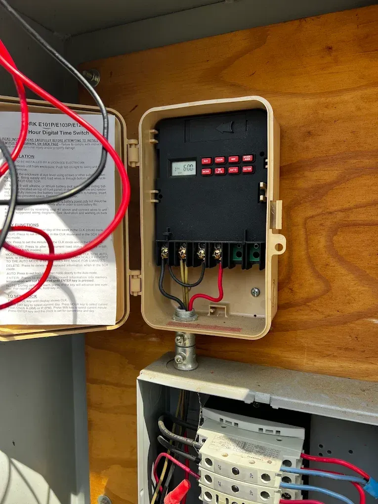 Electrical control boxes with wiring mounted inside a wooden cabinet.